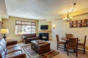 Living room featuring light carpet, a chandelier, and a textured ceiling