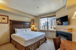 Bedroom with a fireplace and light colored carpet