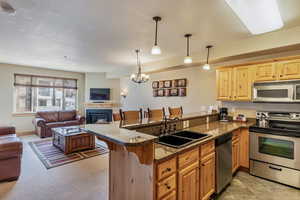 Kitchen with sink, kitchen peninsula, decorative light fixtures, a breakfast bar, and appliances with stainless steel finishes