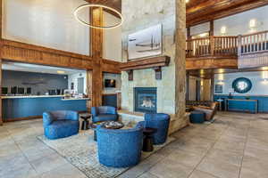 Living room featuring light tile patterned flooring, a stone fireplace, and a high ceiling