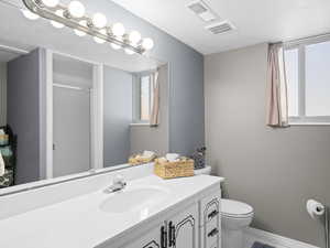 Bathroom featuring vanity, a shower with door, toilet, and a wealth of natural light