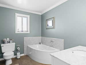 Bathroom with tile patterned floors, vanity, crown molding, a bath, and toilet