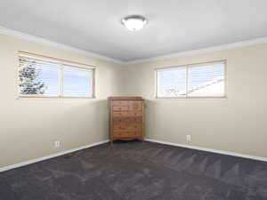 Unfurnished bedroom featuring crown molding and dark colored carpet