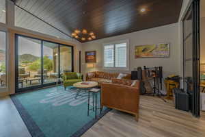 Living room featuring light hardwood / wood-style flooring, wood ceiling, lofted ceiling, and an inviting chandelier