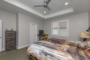 Bedroom featuring a tray ceiling, ceiling fan, and light colored carpet