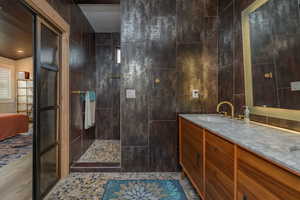 Bathroom with vanity, a shower, tile walls, and vaulted ceiling