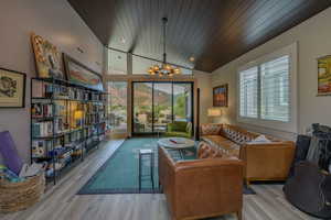 Living room featuring light hardwood / wood-style floors, an inviting chandelier, and wood ceiling