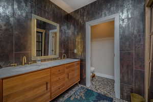 Bathroom featuring vanity, tile walls, and toilet