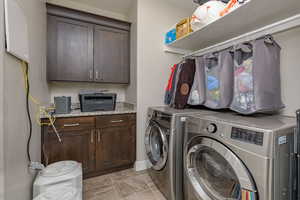 Washroom with cabinets and washing machine and clothes dryer