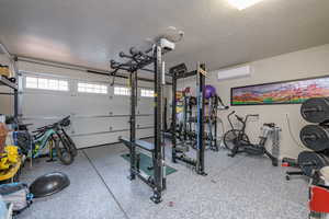 Exercise area featuring a textured ceiling and a wall unit AC