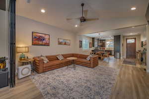 Living room featuring ceiling fan, vaulted ceiling, and light hardwood / wood-style flooring