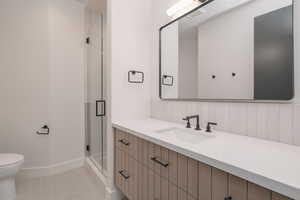 Full bath with vanity, a shower stall, and tile patterned flooring