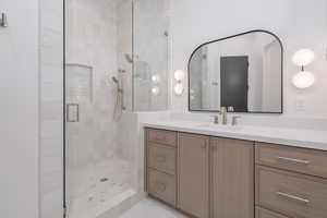 Bathroom with a stall shower, vanity, and marble look tiles