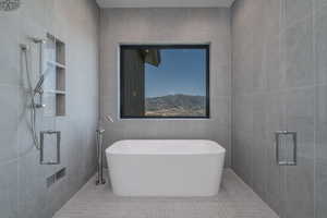 Bathroom with tile walls, a shower stall, and a freestanding tub