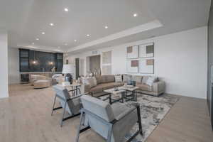 Living room featuring a raised ceiling, beverage cooler, recessed lighting, and light wood finished floors