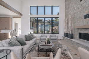 Living area with wood finished floors, a stone fireplace, and a high ceiling