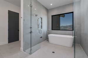 Full bathroom with tile patterned floors, tile walls, a shower stall, a soaking tub, and recessed lighting