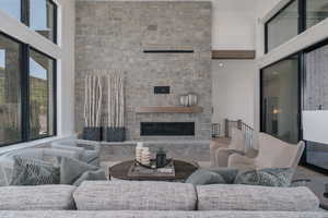 Living area with a towering ceiling, a stone fireplace, and wood finished floors