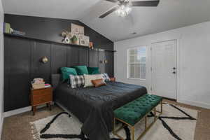 Bedroom featuring light carpet, vaulted ceiling, and ceiling fan.  Door goes to a large deck.