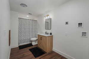 Bathroom with hardwood / wood-style floors, vanity, toilet, and a shower with shower curtain