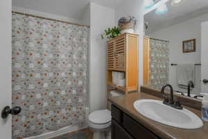 Full bathroom featuring vanity, shower / bath combo, and toilet