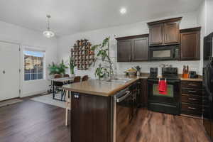 Kitchen featuring dark brown cabinets, sink, black appliances, and decorative light fixtures