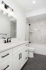 Full bathroom with tile patterned flooring, vanity, shower / bath combo, and toilet