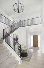 Staircase featuring wood-type flooring, a towering ceiling, and an inviting chandelier