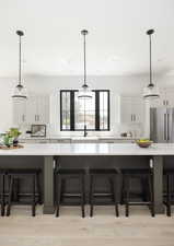 Kitchen with pendant lighting, white cabinetry, high end fridge, and sink