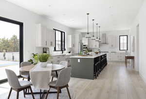 Kitchen with plenty of natural light, wall chimney range hood, a center island, and decorative light fixtures