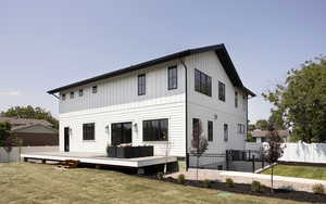 Back of house featuring a lawn and a wooden deck