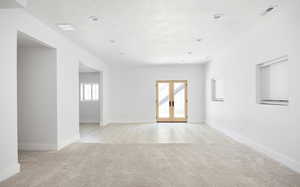 Empty room with french doors, light colored carpet, and a textured ceiling