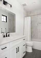 Full bathroom featuring tile patterned floors, vanity, shower / bath combination with curtain, and toilet