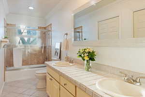 Full bathroom with double vanity, dual closets and neutral tile throughout