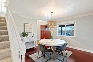 Dining room with Rattan Chandelier, hardwood floors and crown molding