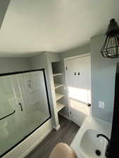 Bathroom with wood-type flooring, vanity, an inviting chandelier, and bath / shower combo with glass door