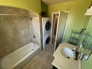 Bathroom featuring tile patterned floors, vanity, stacked washer and dryer, and tiled shower / bath