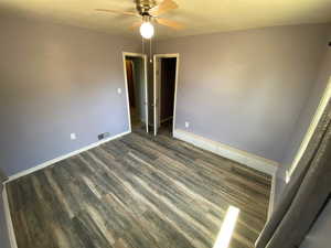 Interior space with ceiling fan, a spacious closet, dark wood-type flooring, and a closet