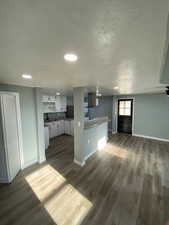 Kitchen with dark hardwood / wood-style flooring, a textured ceiling, ventilation hood, sink, and white cabinetry