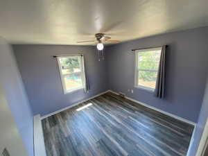 Empty room featuring a wealth of natural light, ceiling fan, and dark hardwood / wood-style floors