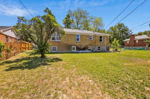 Back of property with brick siding, fence, and a yard