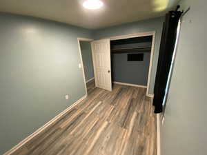 Unfurnished bedroom featuring dark hardwood / wood-style flooring and a closet