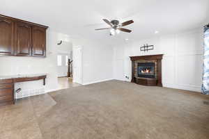 Unfurnished living room with ceiling fan, a stone fireplace, and light tile patterned floors