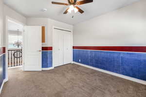 Unfurnished bedroom with a closet, carpet, and ceiling fan with notable chandelier