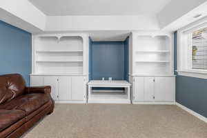 Living room featuring carpet, a textured ceiling, a tray ceiling, and built in features