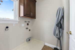 Washroom featuring hookup for an electric dryer, cabinets, tile patterned floors, and washer hookup