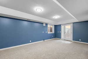 Carpeted spare room featuring a textured ceiling and a raised ceiling