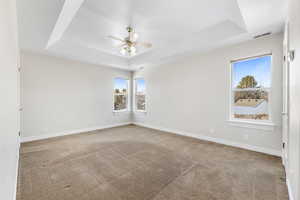 Carpeted spare room featuring ceiling fan, a raised ceiling, and a textured ceiling