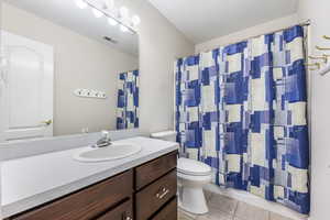 Bathroom featuring tile patterned floors, vanity, toilet, and a textured ceiling