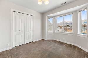 Unfurnished bedroom with carpet, a mountain view, a closet, and multiple windows